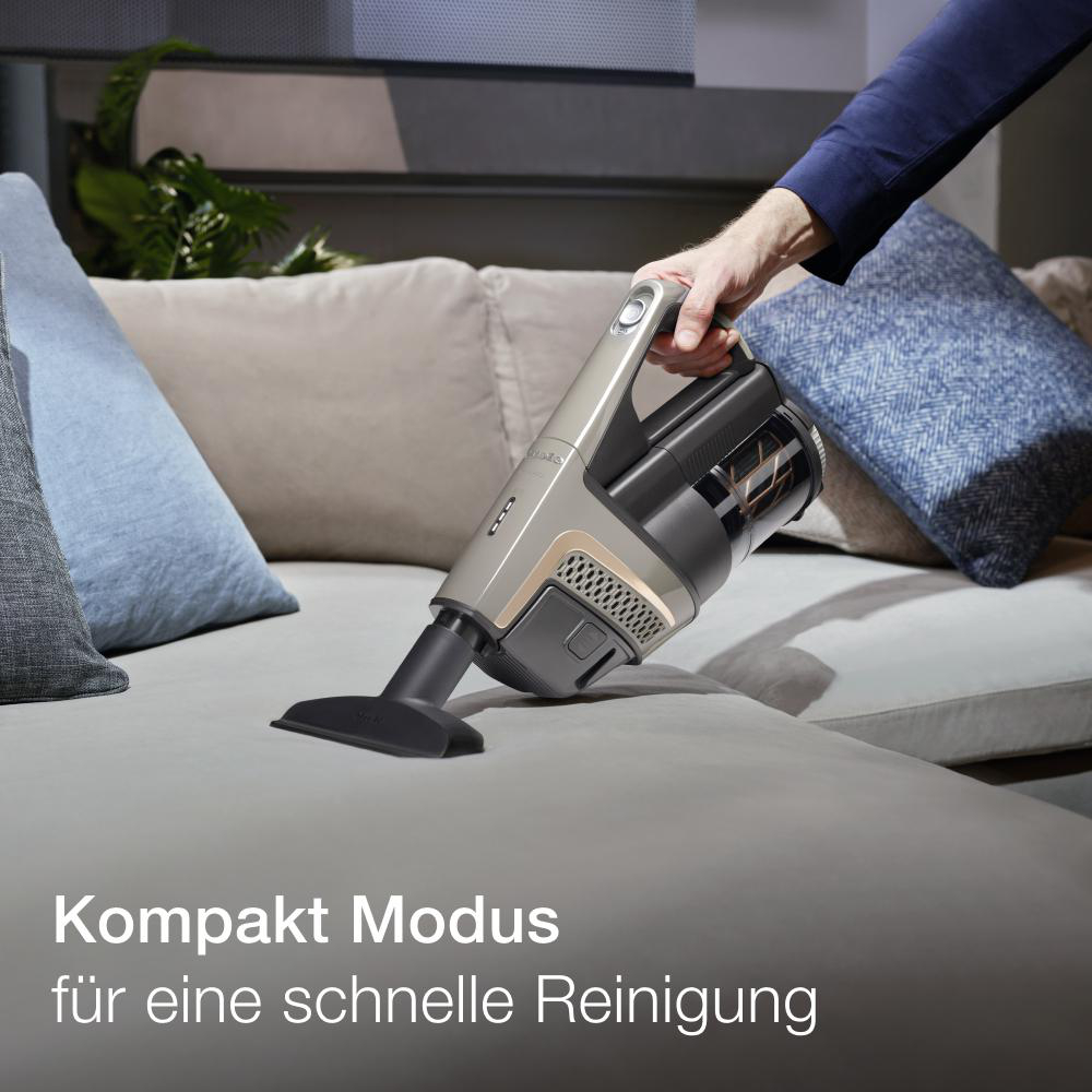 Eine Person verwendet einen Handstaubsauger auf einem Sofa. Der Text handelt vom Reinigen.