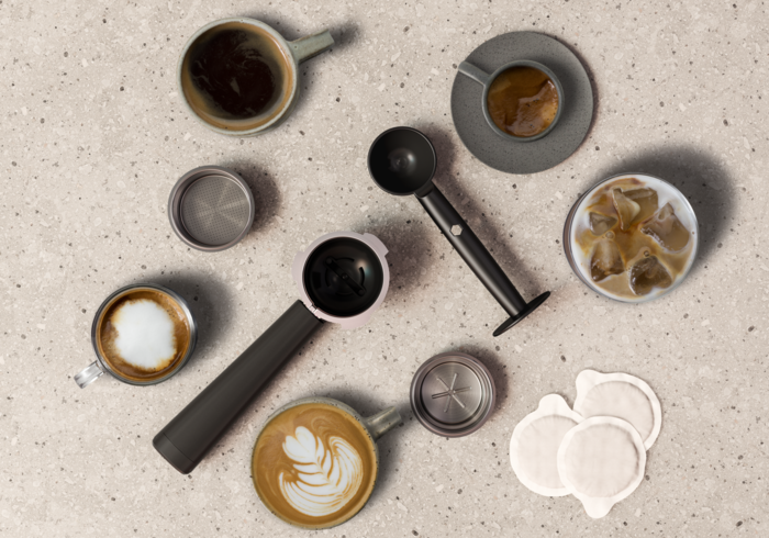 Kávé összeállítás: eszpresszó, latte art, jeges kávé, szűrőtartó, kanál, szűrők és kávépárnák pöttyös felületen.