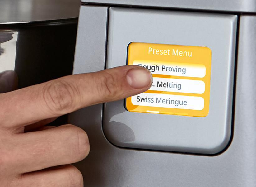 Hand drückt Touchscreen mit Menüoptionen: Teiggehen, Schmelzen, Schweizer Baiser.