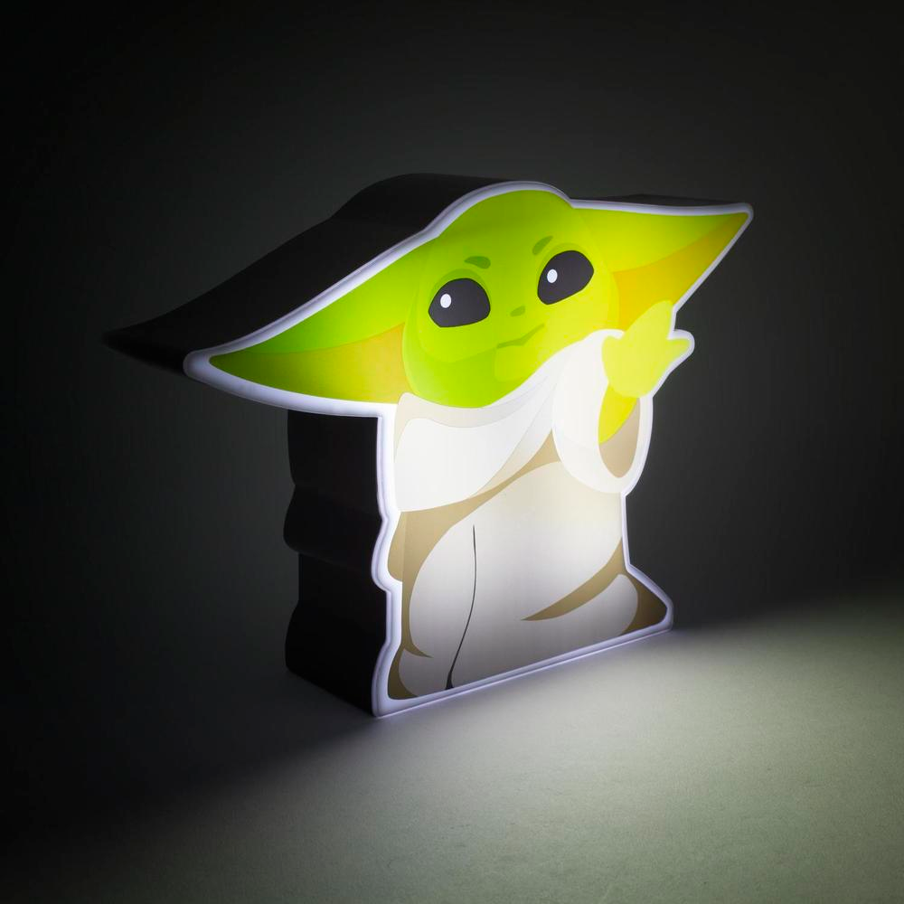 Egy világító The Child (Baby Yoda) figura, fehér köntössel és zöld fejjel, sötét háttérben.