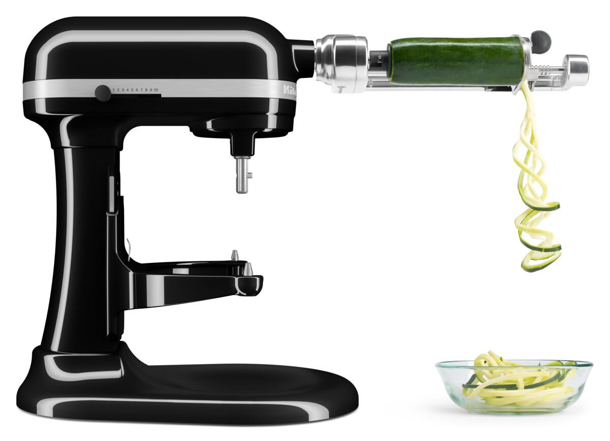 Schwarzer KitchenAid-Küchenmixer mit Zucchini-Spiralschneider. Spiralförmige Zucchini fällt in eine Glasschüssel.