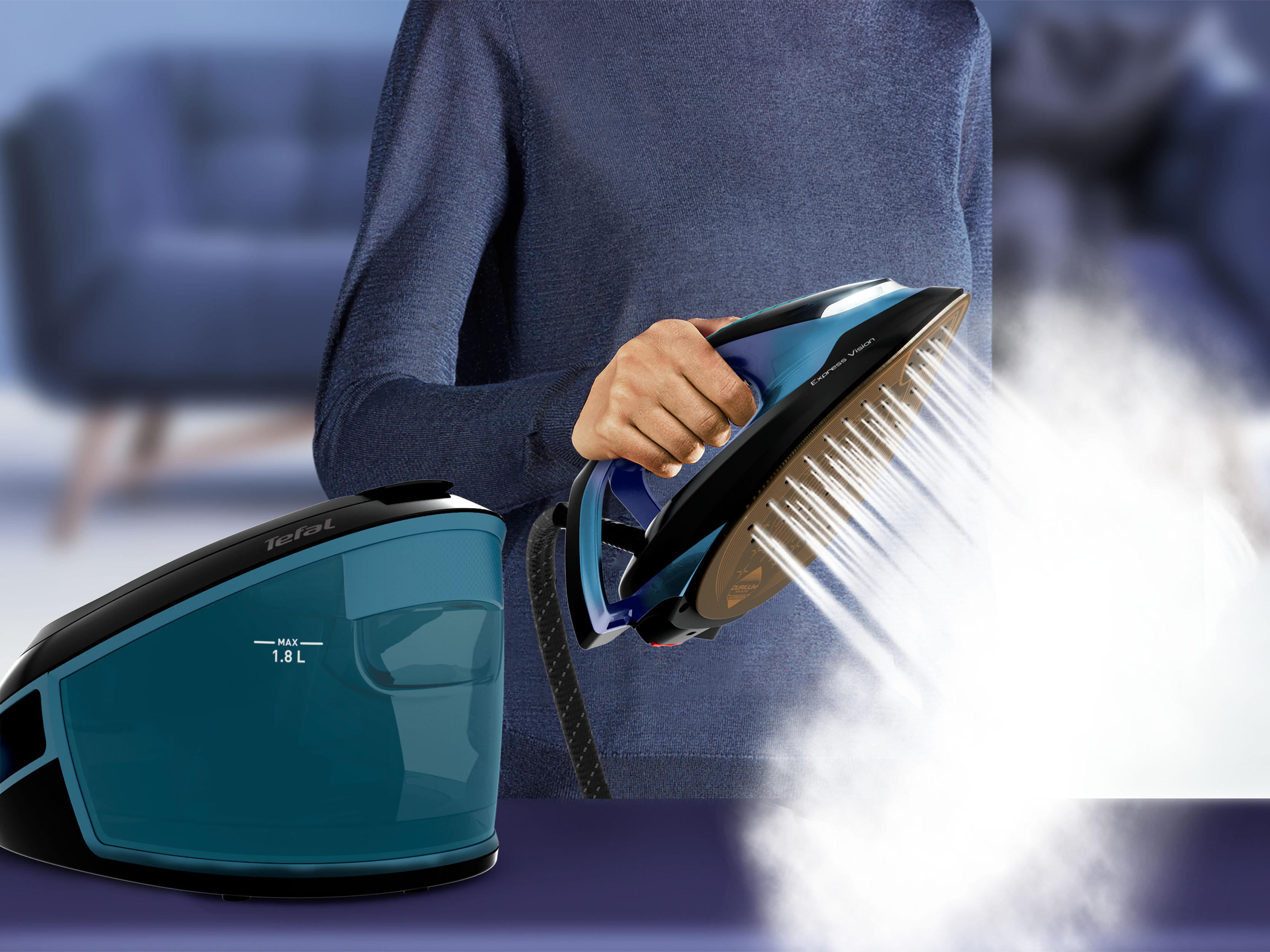 Eine Person bügelt Kleidung mit einem blau-schwarzen Bügeleisen, Dampf vorhanden.