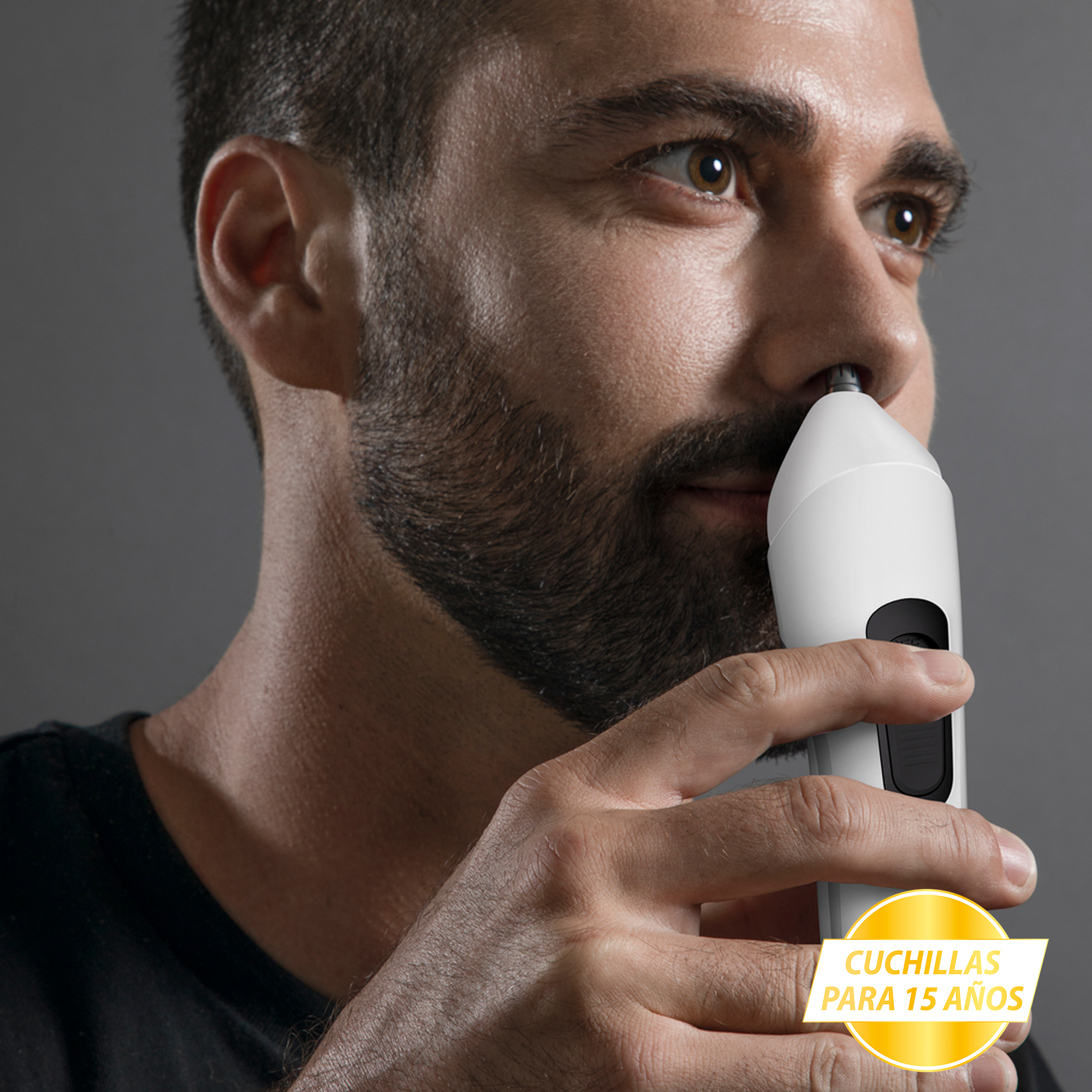 Hombre usando un recortador de vello nasal. Primer plano. Texto: Cuchillas para 15 años.