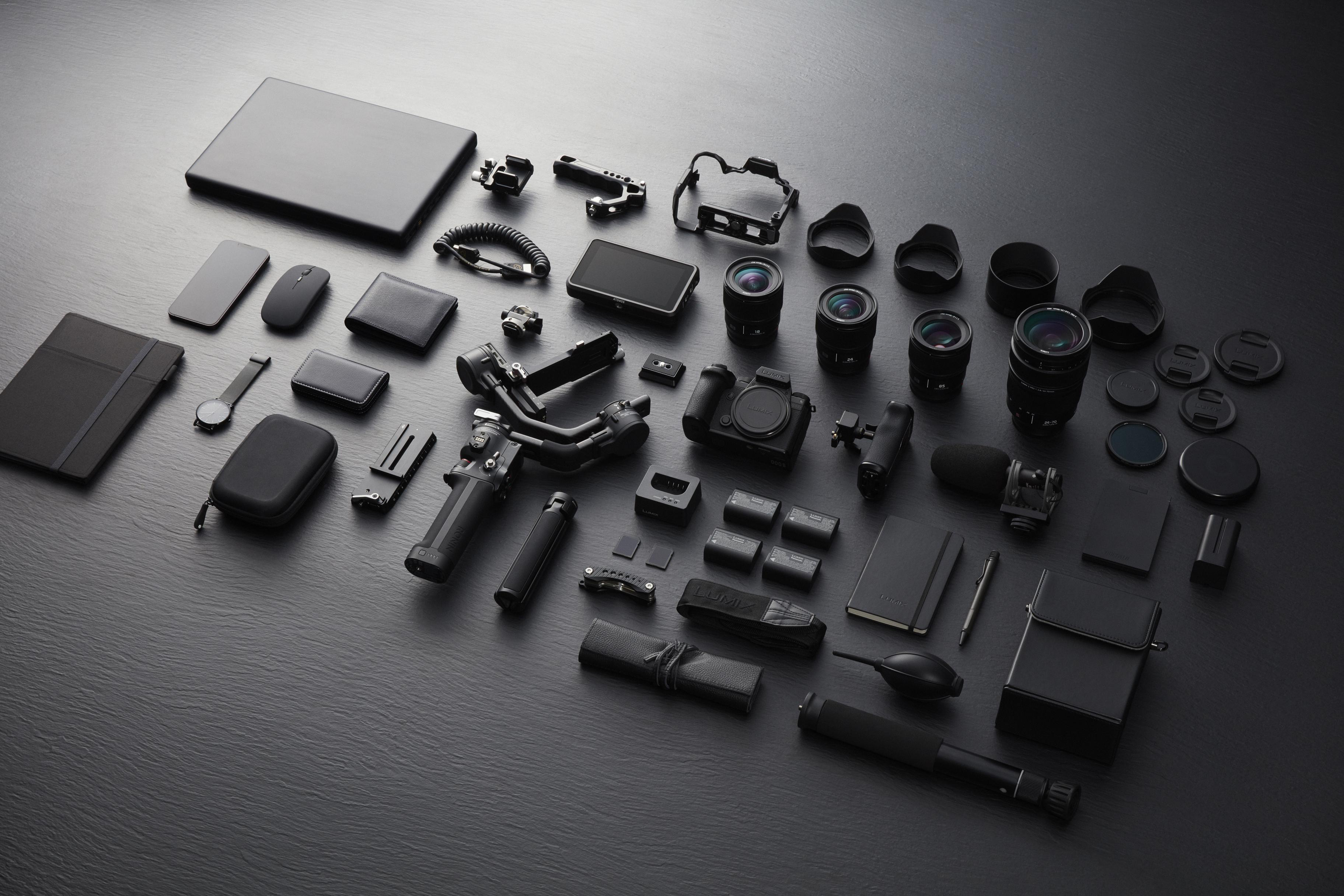 Eine Sammlung von schwarzem Fotoequipment auf einer dunklen Oberfläche.