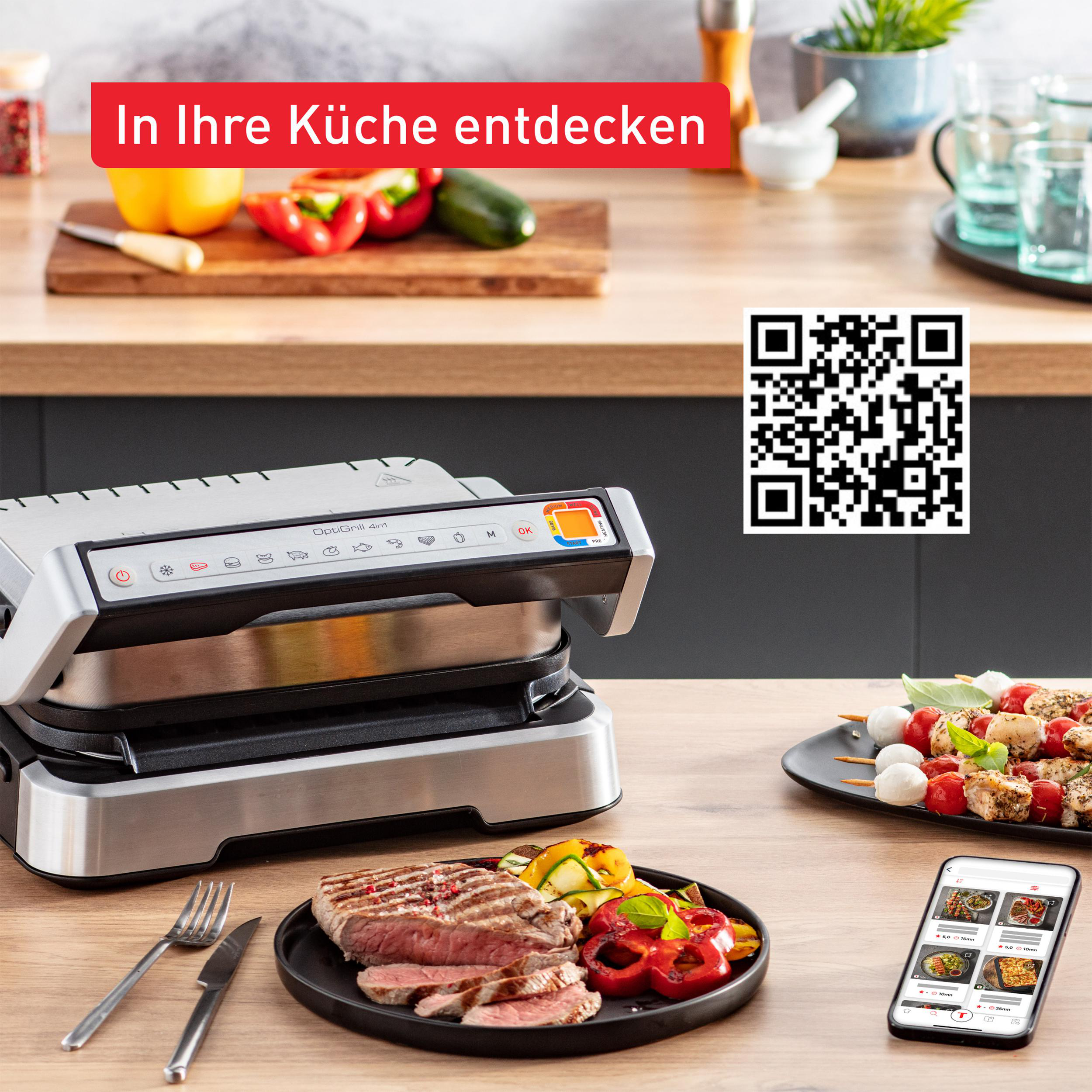 Eine Küchenszene mit Grill, Essen und einem Smartphone, das eine Rezept-App anzeigt.