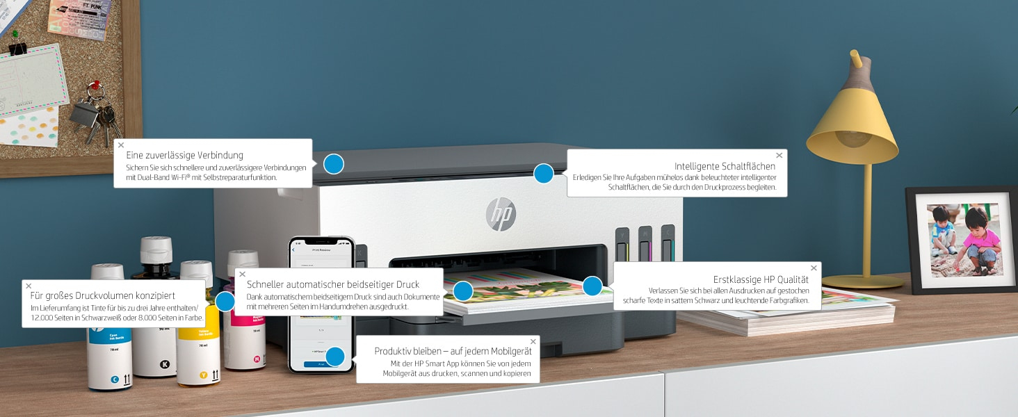 Drucker und Tintenflaschen auf einer Holzoberfläche. Ein Smartphone zeigt die HP Smart App an.