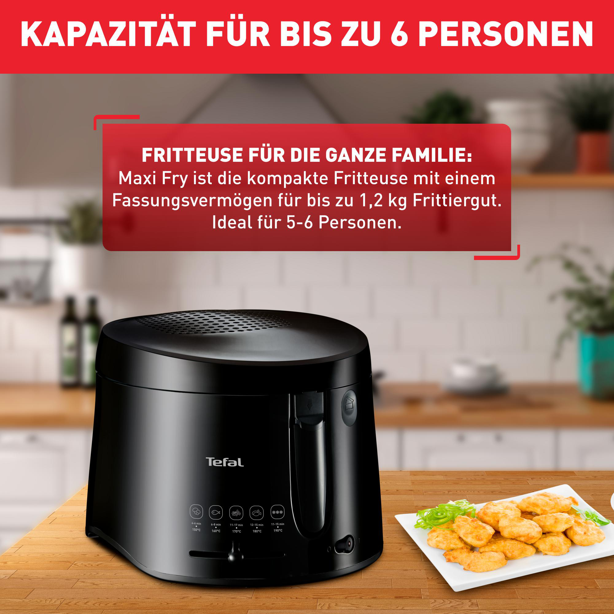 Schwarze Tefal-Fritteuse mit Essen auf einem Teller, auf einem Holztisch, vor verschwommener Küche.