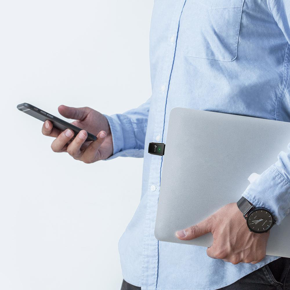 Ein Mann hält ein Telefon und einen Laptop, mit einem kleinen schwarzen Gerät an seinem Hemd.