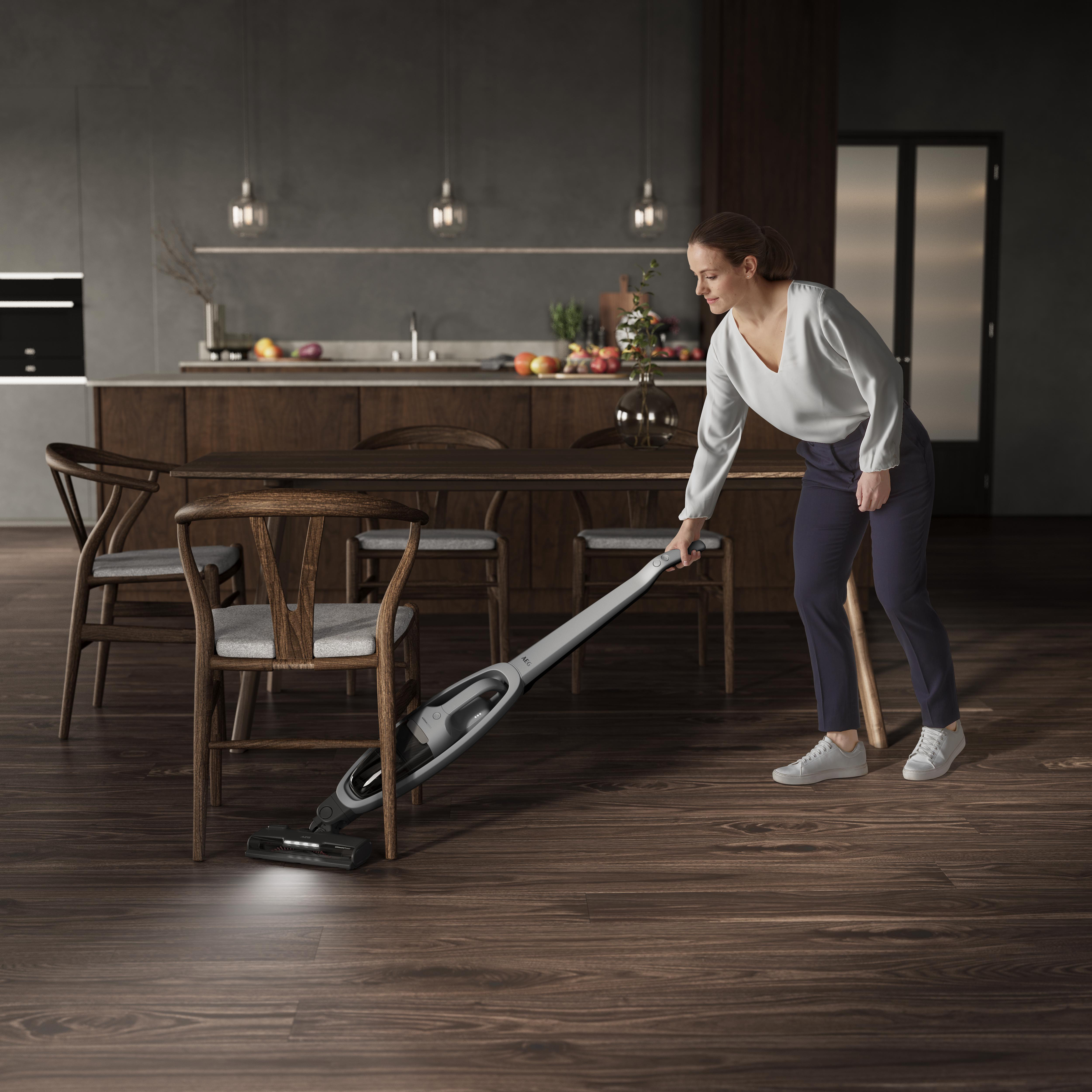 Eine Frau, die einen Holzboden in einem modernen, lichtdurchfluteten Raum saugt.