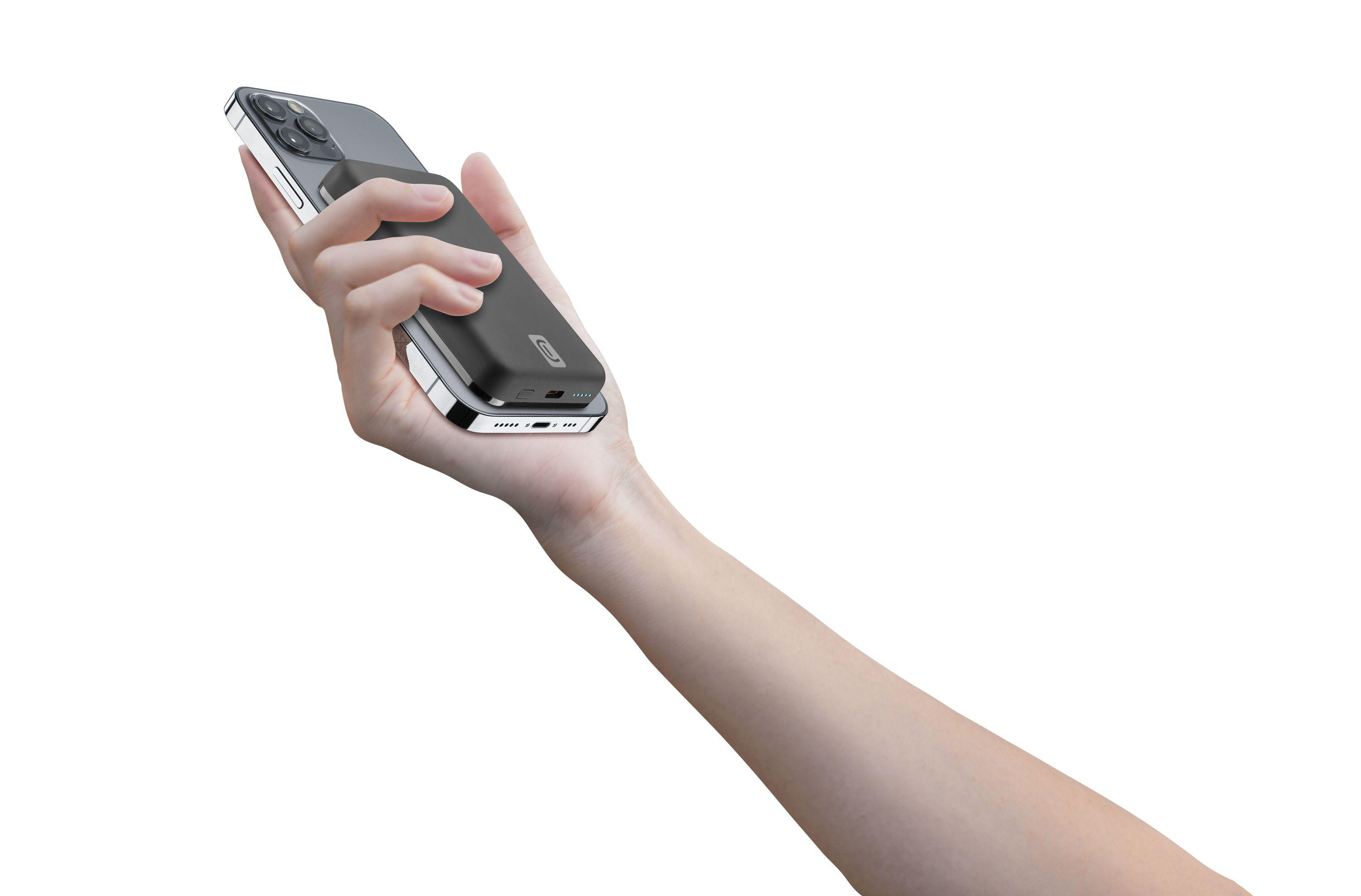 Eine Hand hält eine schwarze Powerbank, die an einem silbernen Telefon befestigt ist, isoliert auf Weiß.