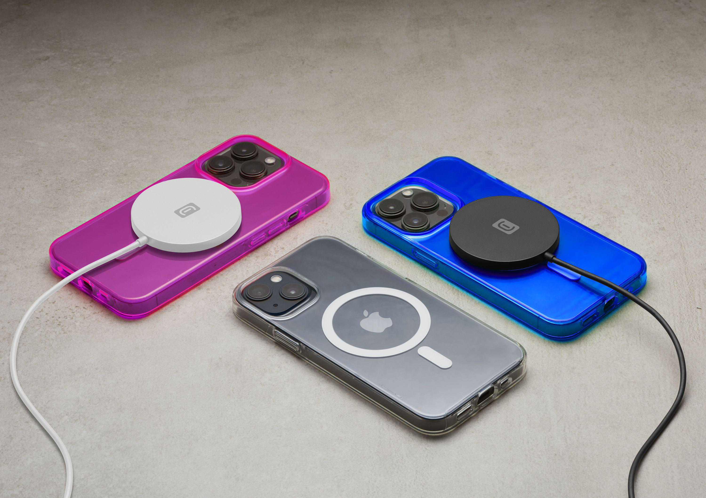Drei iPhones auf einer Oberfläche, jeweils mit einem kabellosen Ladegerät.