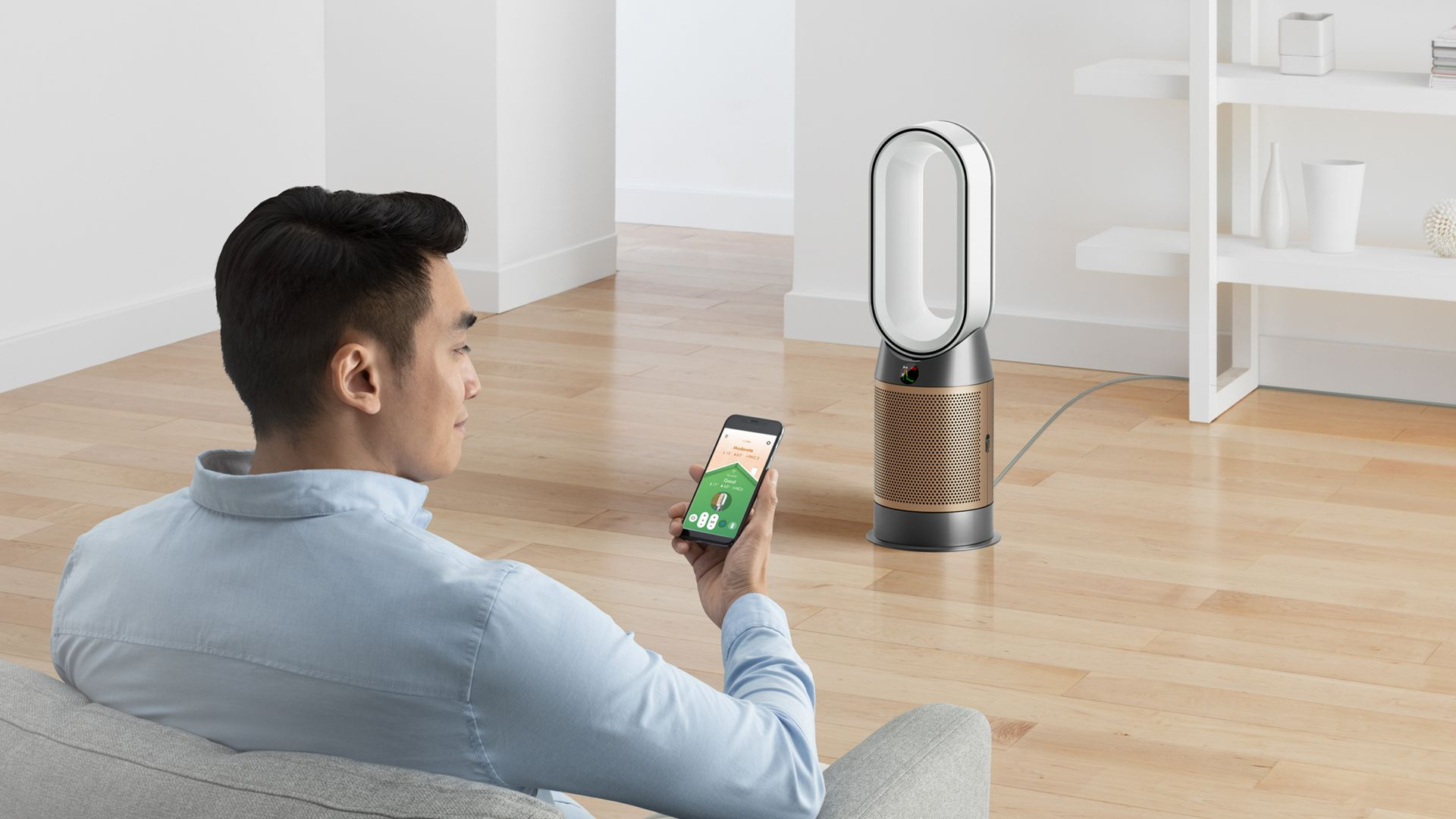Adam, Dyson fanını kontrol eden bir telefona bakıyor.