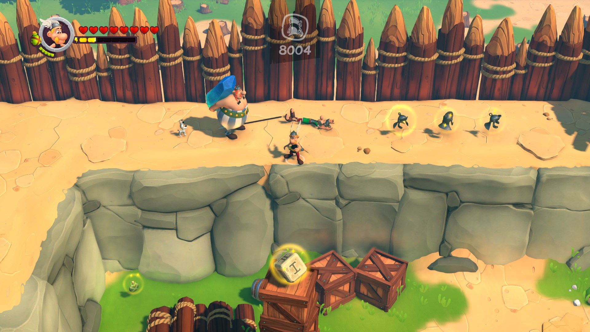 Spiel-Screenshot von Asterix, der in einer Arena kämpft. Holzkisten und Zaun.