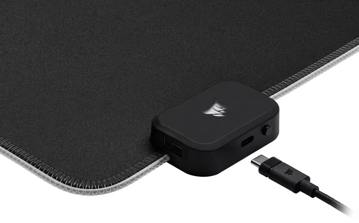 Fekete egérpad fekete töltőelosztóval. USB kábel csatlakoztatva. Fekete háttér.