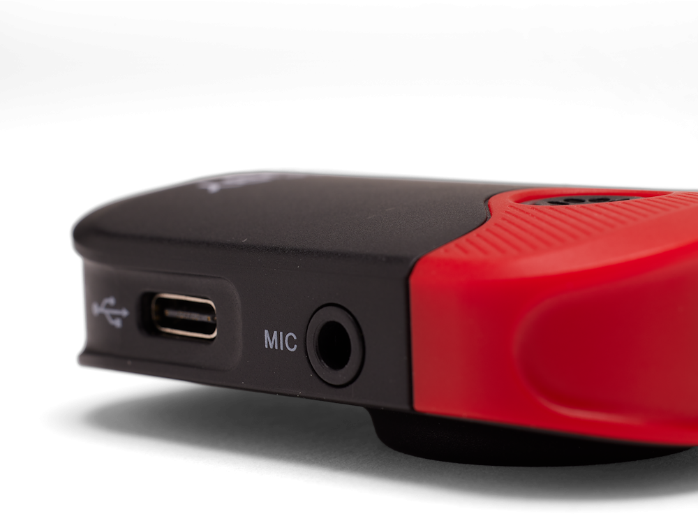 Nahaufnahme eines roten und schwarzen Geräts mit USB-Anschluss und Mikrofoneingang auf schwarzem Hintergrund.