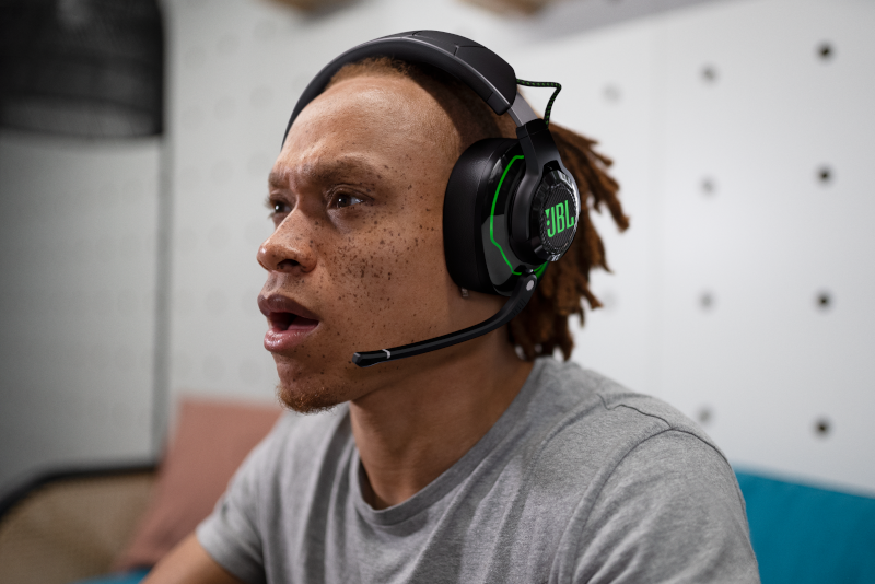 Ein Mann mit einem JBL-Headset mit Mikrofon blickt mit überraschtem Gesichtsausdruck zur Seite.