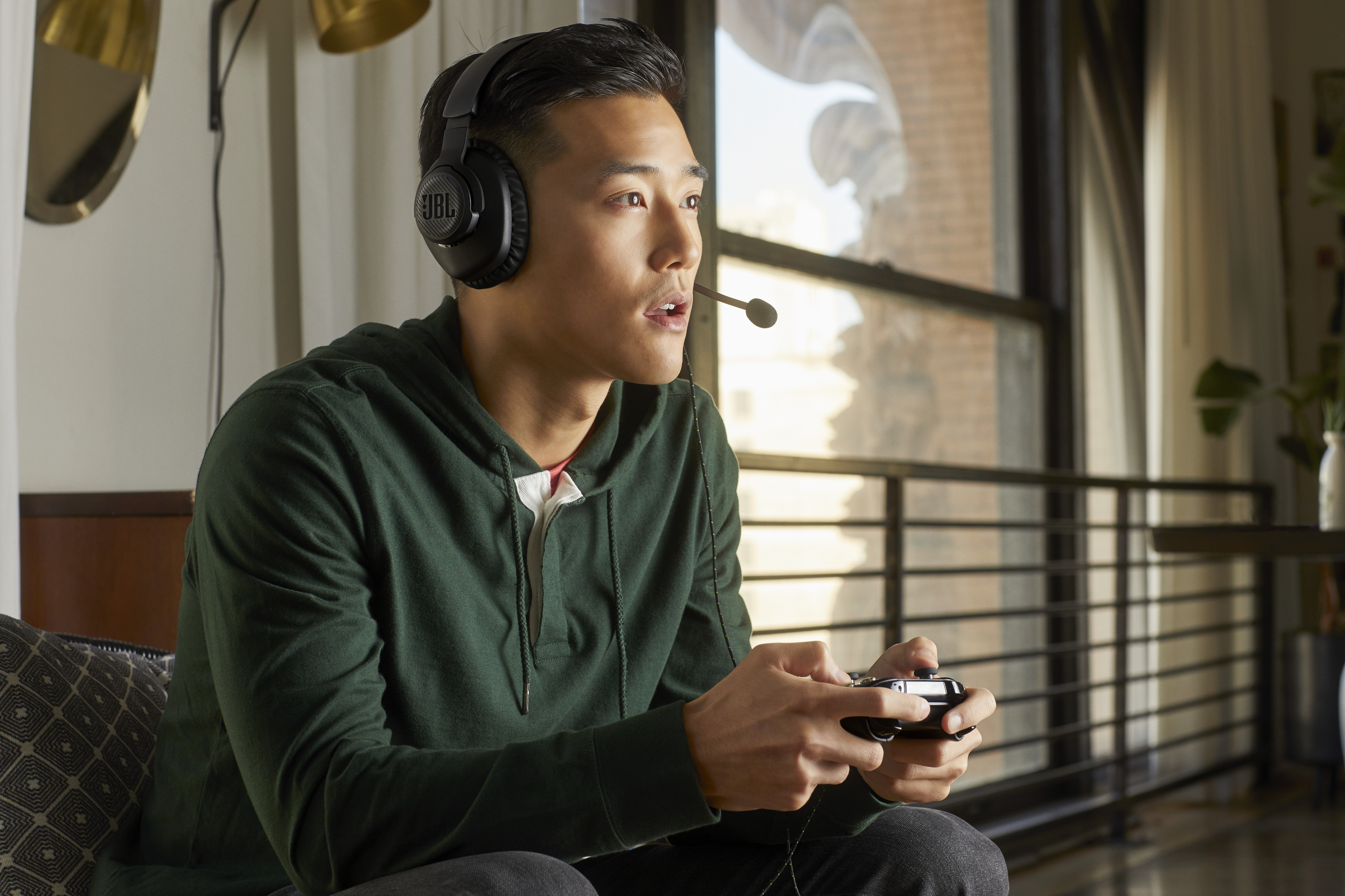 Ein Mann spielt ein Videospiel mit einem Controller, trägt ein Headset, drinnen, tagsüber.