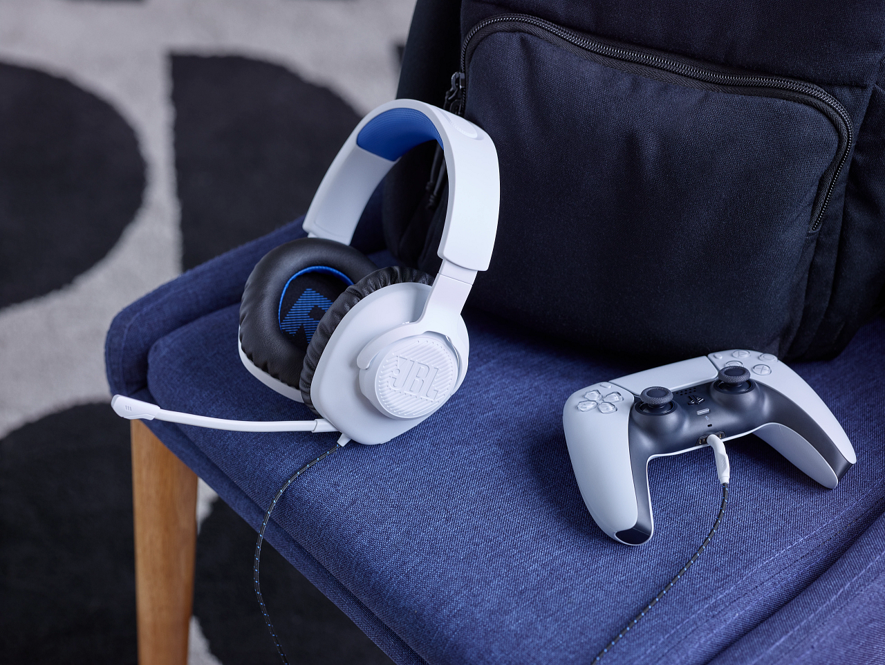 Weißes JBL-Headset, Controller und Rucksack auf blauem Stuhl.