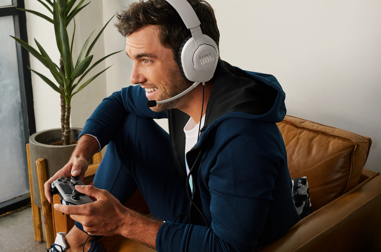 Ein Mann mit Kopfhörern spielt ein Spiel. Er hält einen Controller.