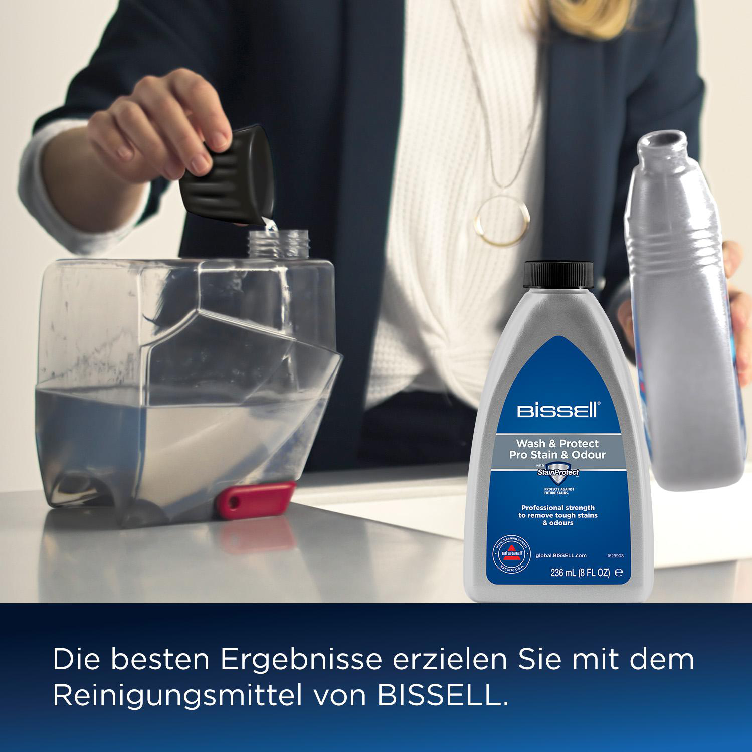 Person gießt Flüssigkeit in einen Reinigerbehälter, daneben eine Flasche.
