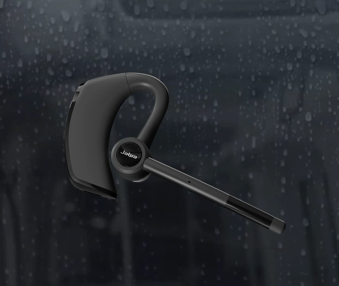 Egy fekete Jabra Bluetooth headset látható, a Jabra logóval. A háttér egy elmosódott, esős jelenet.