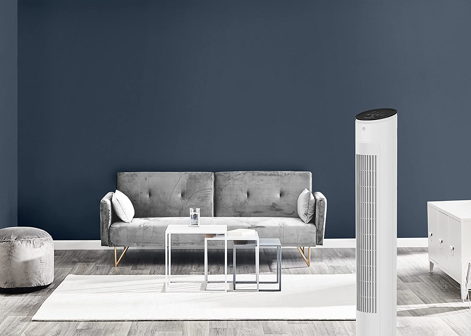 Un soggiorno moderno con divano, tavolini, tappeto e ventilatore a torre.