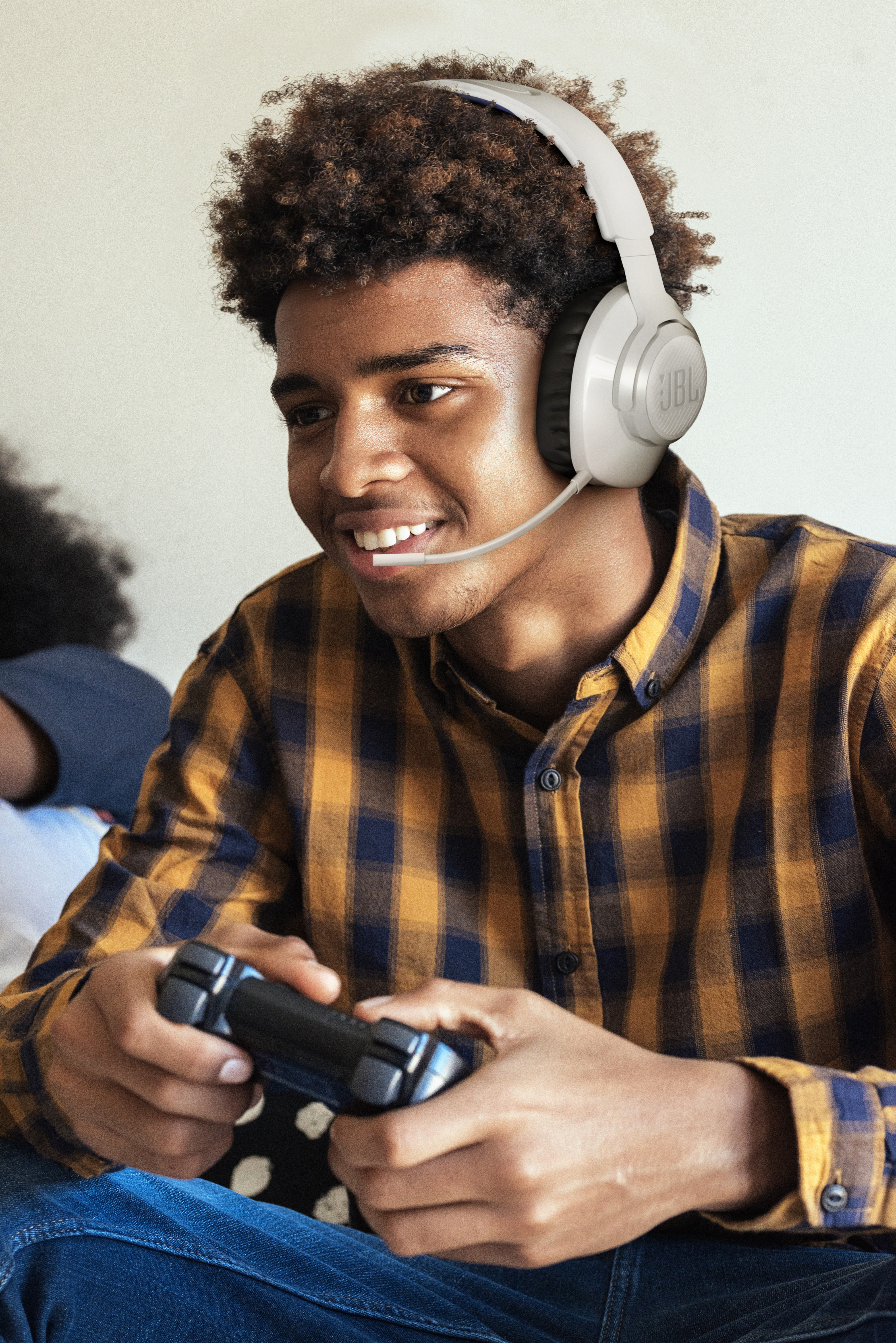 Ein junger Mann mit einem weißen Headset spielt mit einem Controller ein Videospiel.