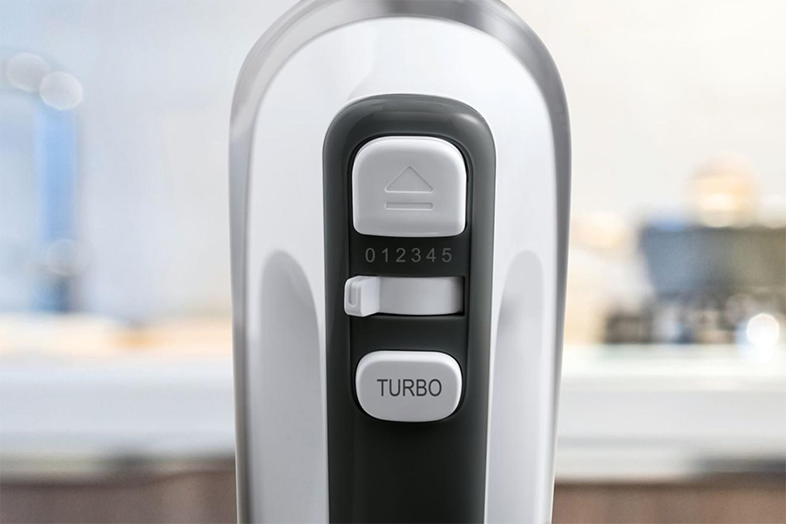 Egy mixer vezérlőpaneljének közeli képe. Van rajta egy számozott tárcsa és egy turbó gomb.