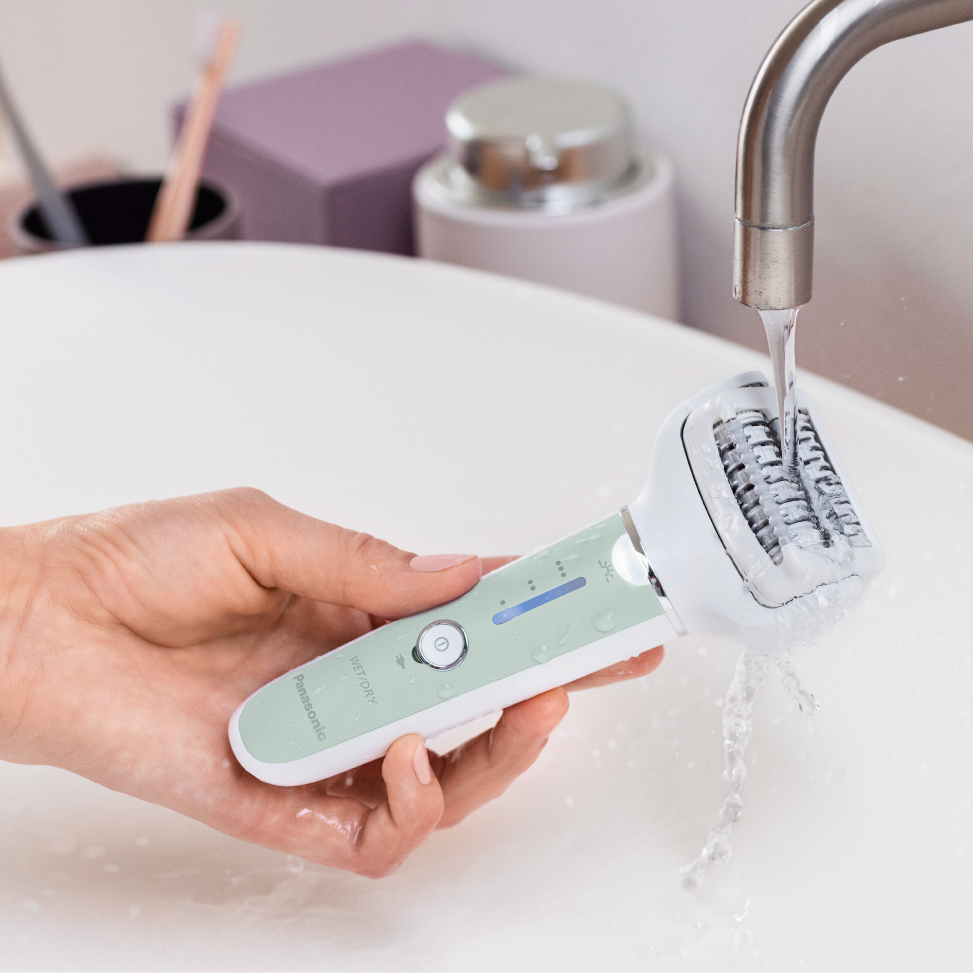 Eine Hand benutzt einen Panasonic Nass-/Trockenrasierer unter fließendem Wasser in einem Waschbecken.