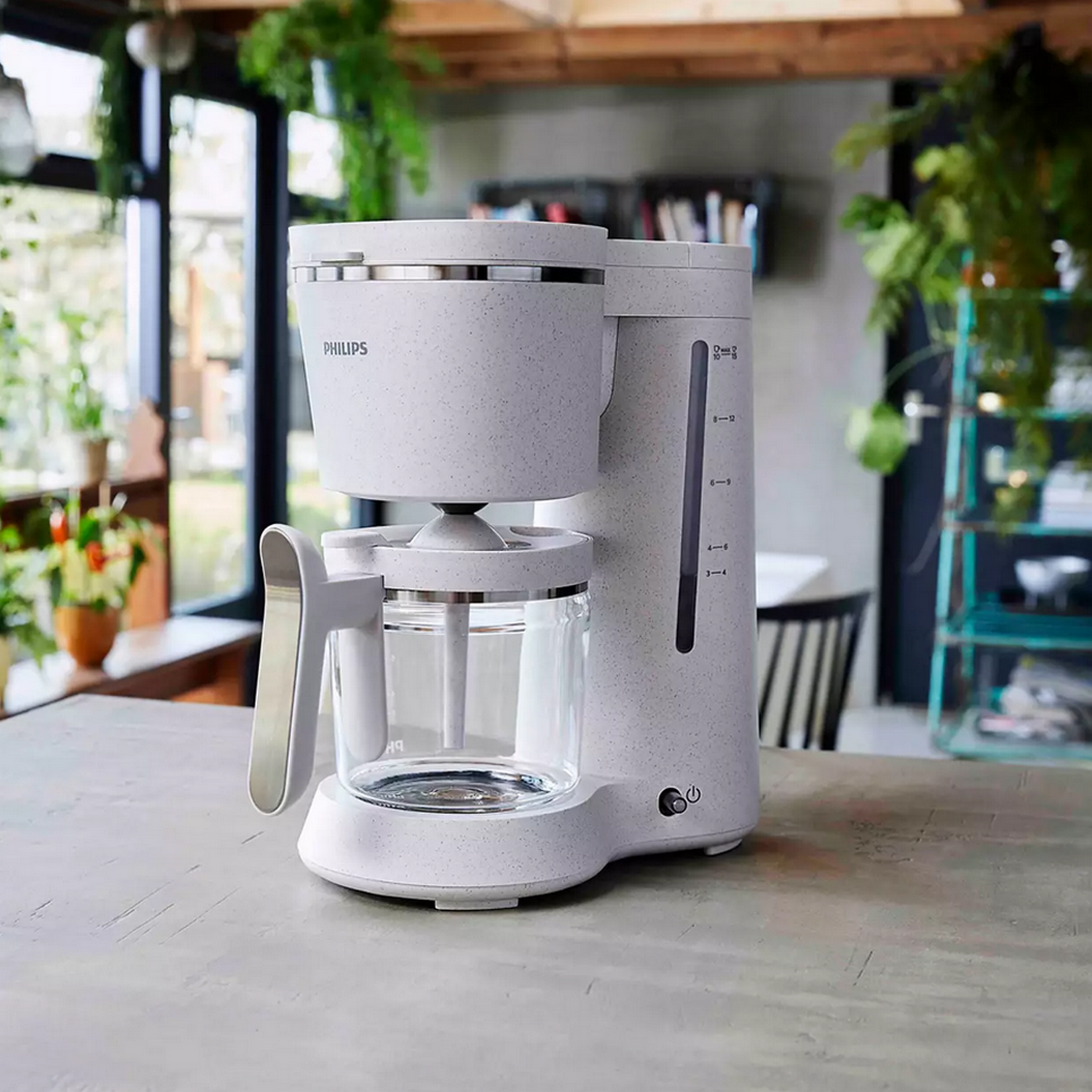 White Philips coffee maker on a gray countertop with a glass carafe.