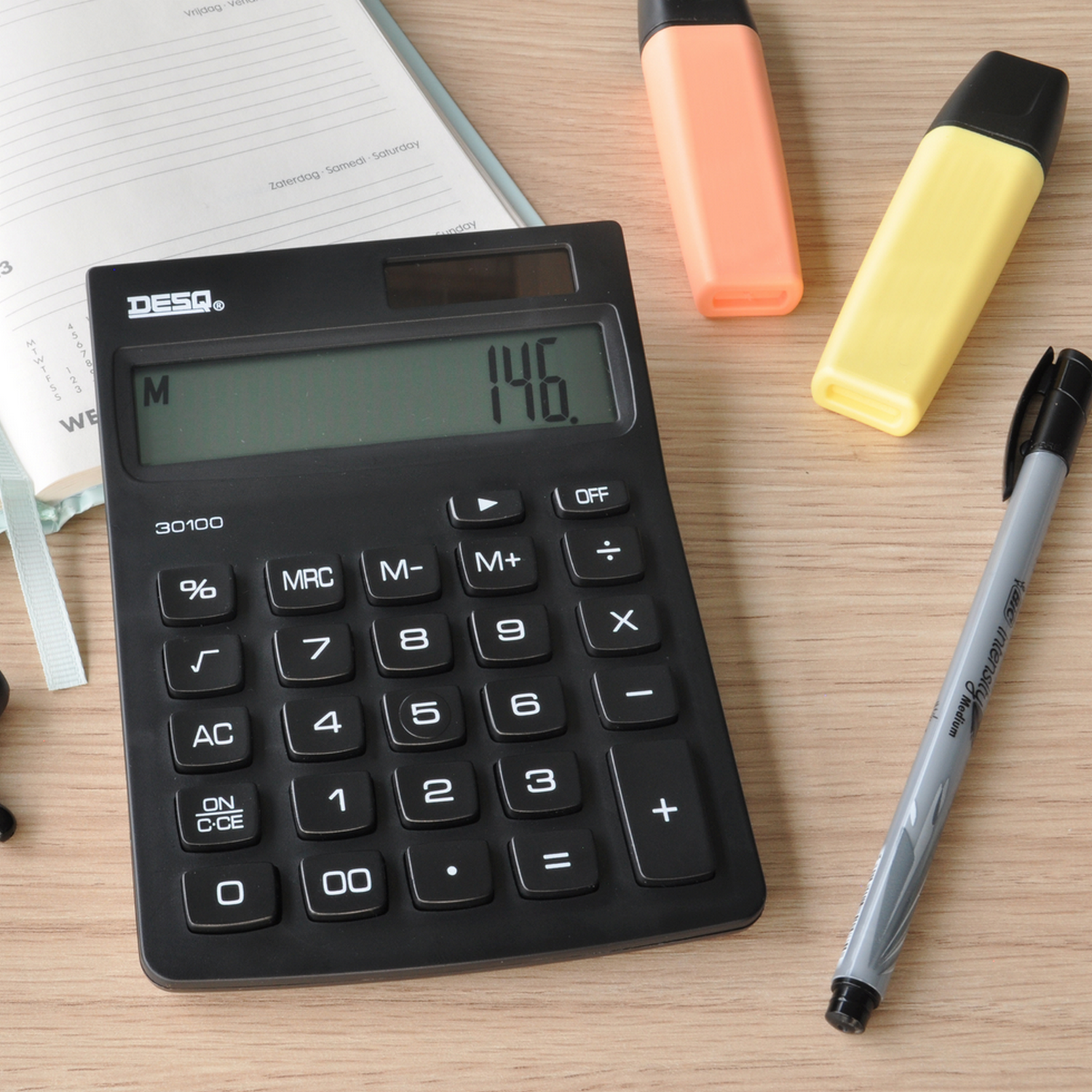 Black calculator with the number 146 displayed on a wooden surface, with markers.