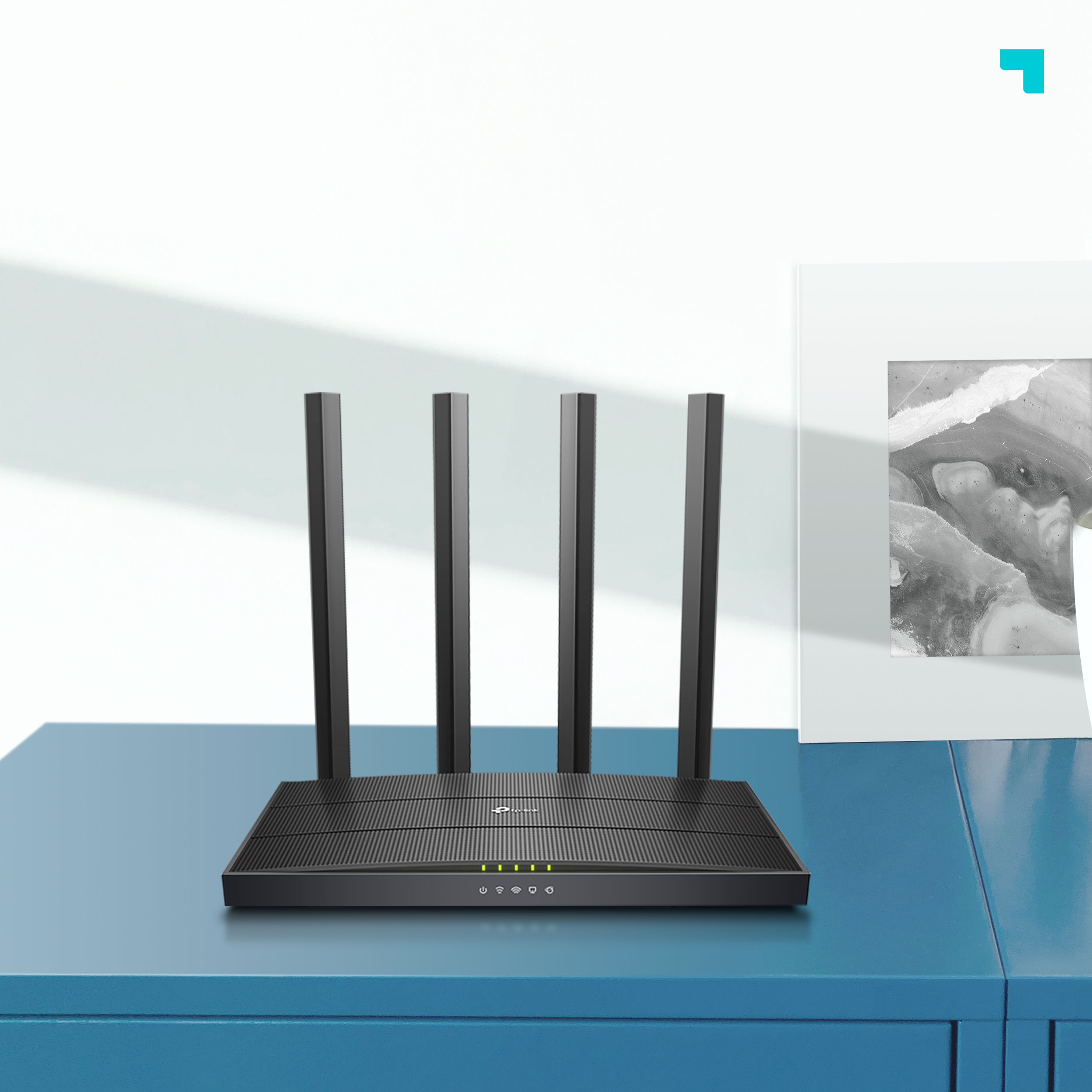 Un enrutador negro con cuatro antenas, colocado sobre una mesa azul.