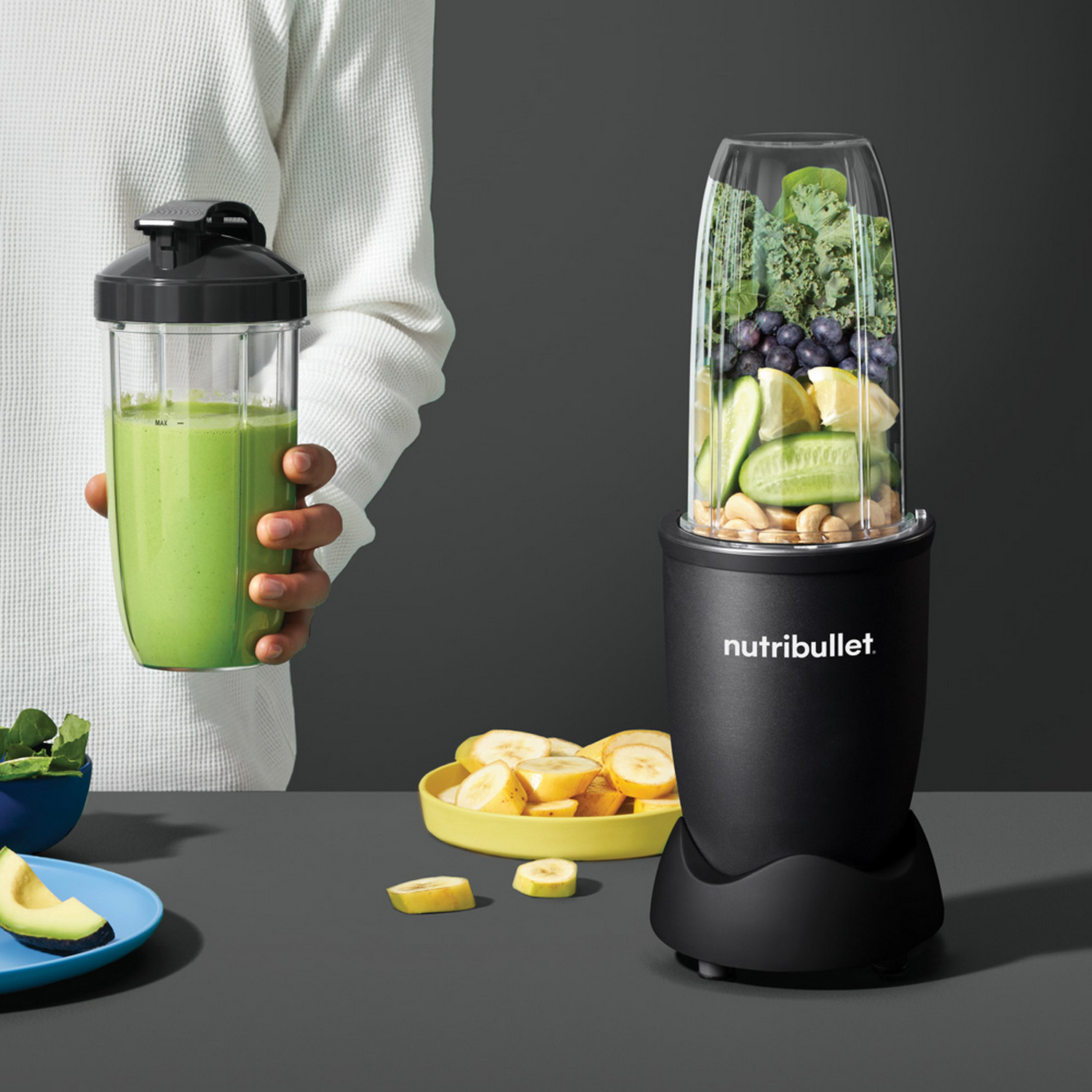 A person is holding a green smoothie in a transparent container.