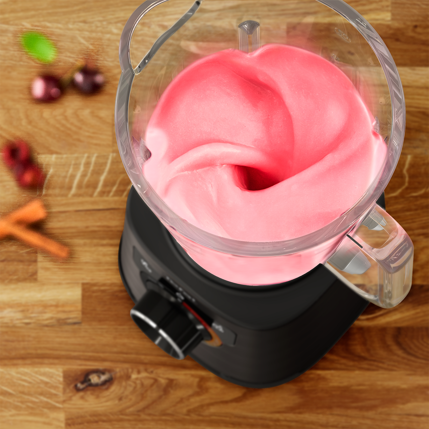 A blender with pink mixture inside, set on a wooden surface.