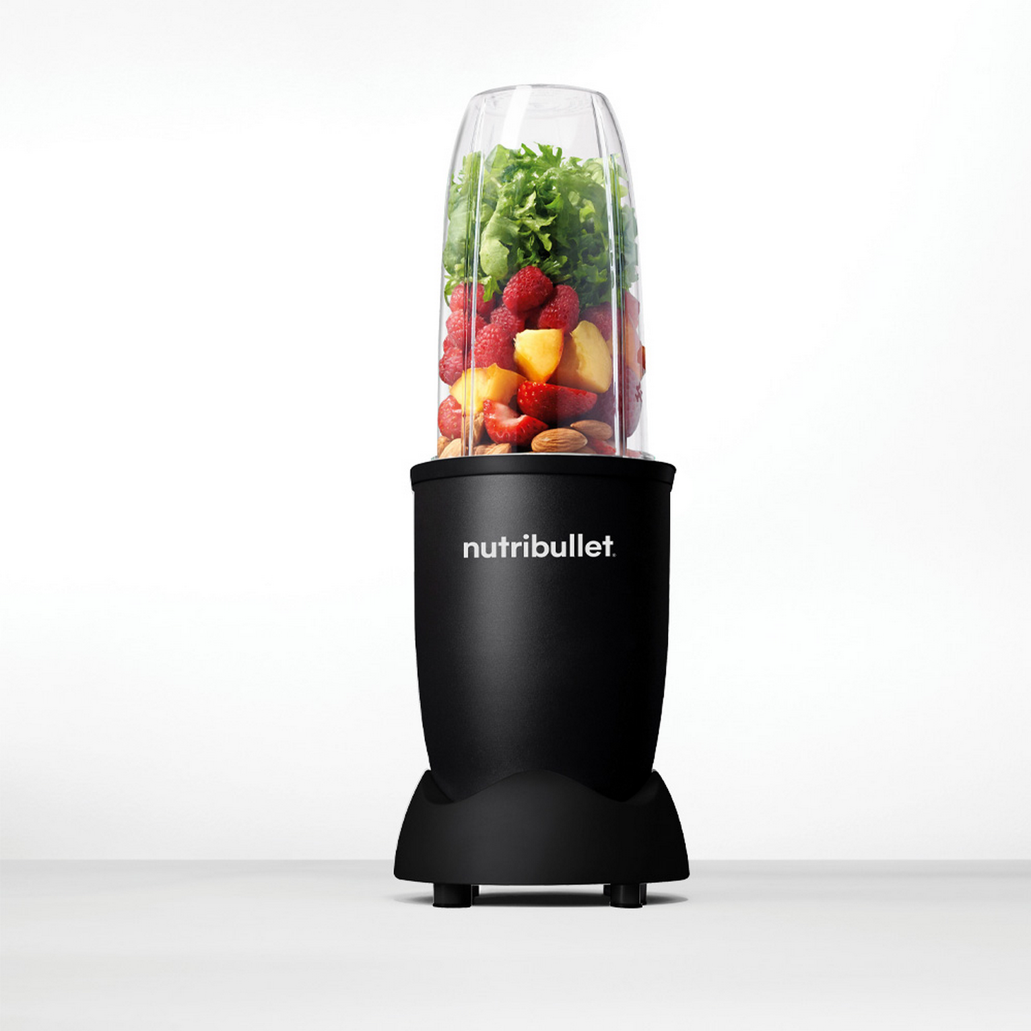 A black Nutribullet blender with fruits and vegetables in the container.