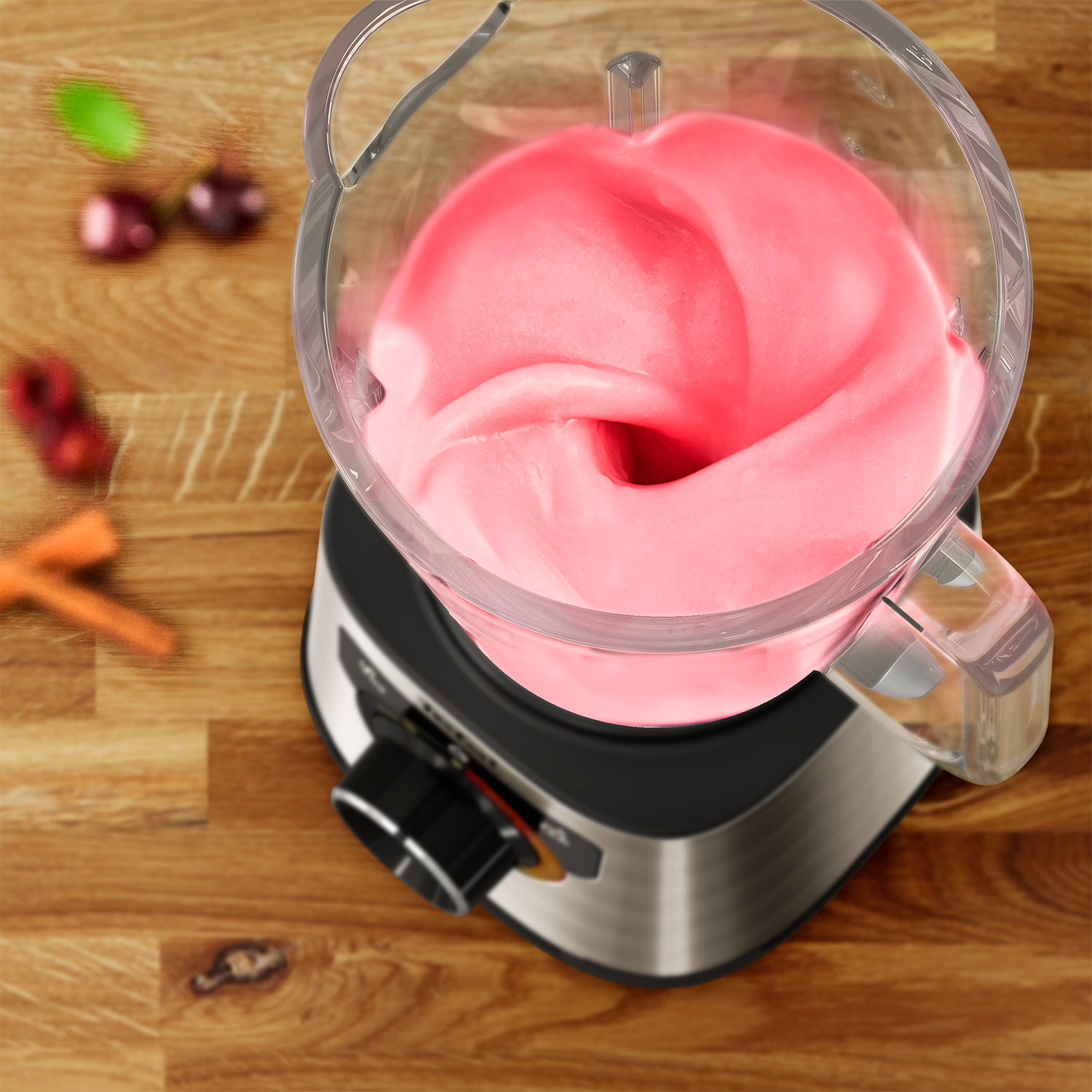 Blender with pink liquid. Cherries and carrots are on the wooden surface.