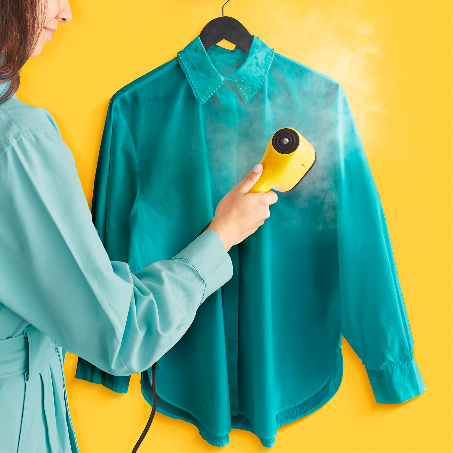 A person ironing a navy blue garment with a black and blue iron.