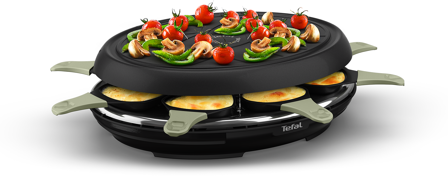 Raclette grill with vegetables on top and cheese in pans below, all on a black surface.