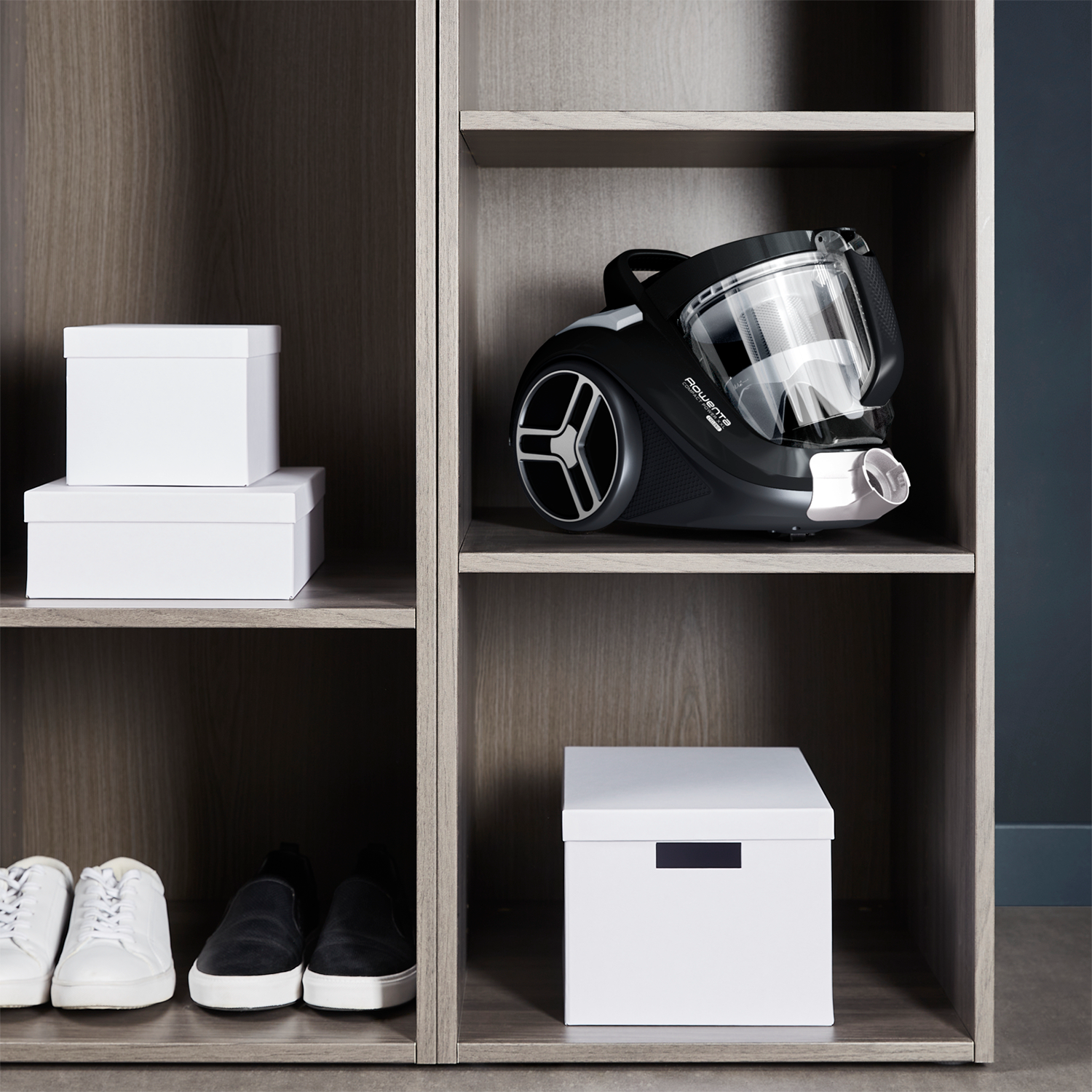 A vacuum cleaner and white boxes in a storage unit.