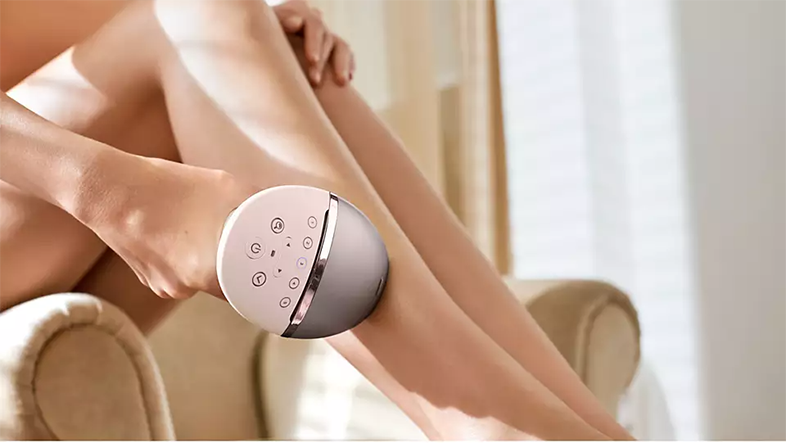 Nő szőrtelenítőt használ a lábán. A szőrtelenítő kerek és rózsaszínes.