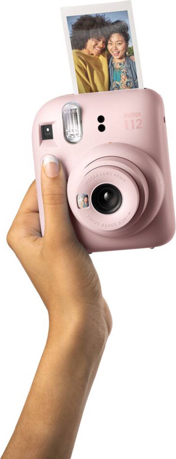 Hand, die eine rosa Instax-Kamera hält, wobei ein Foto herauskommt.