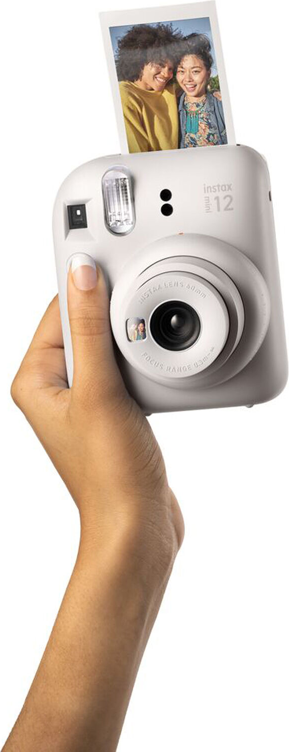 La mano di una persona tiene una fotocamera istantanea bianca con una foto.