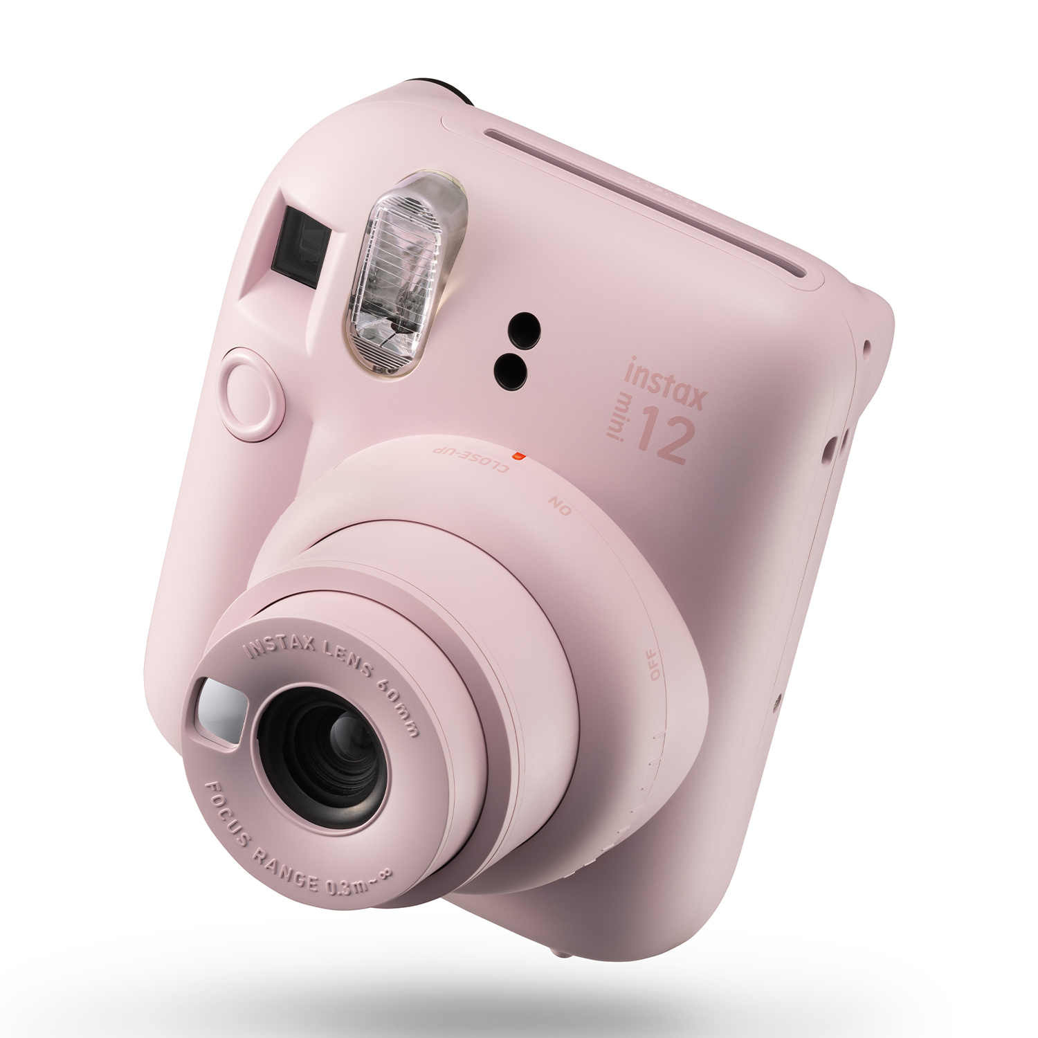 Fotocamera istantanea rosa Instax Mini 12, con obiettivo e flash, su superficie bianca, che mostra il lato.