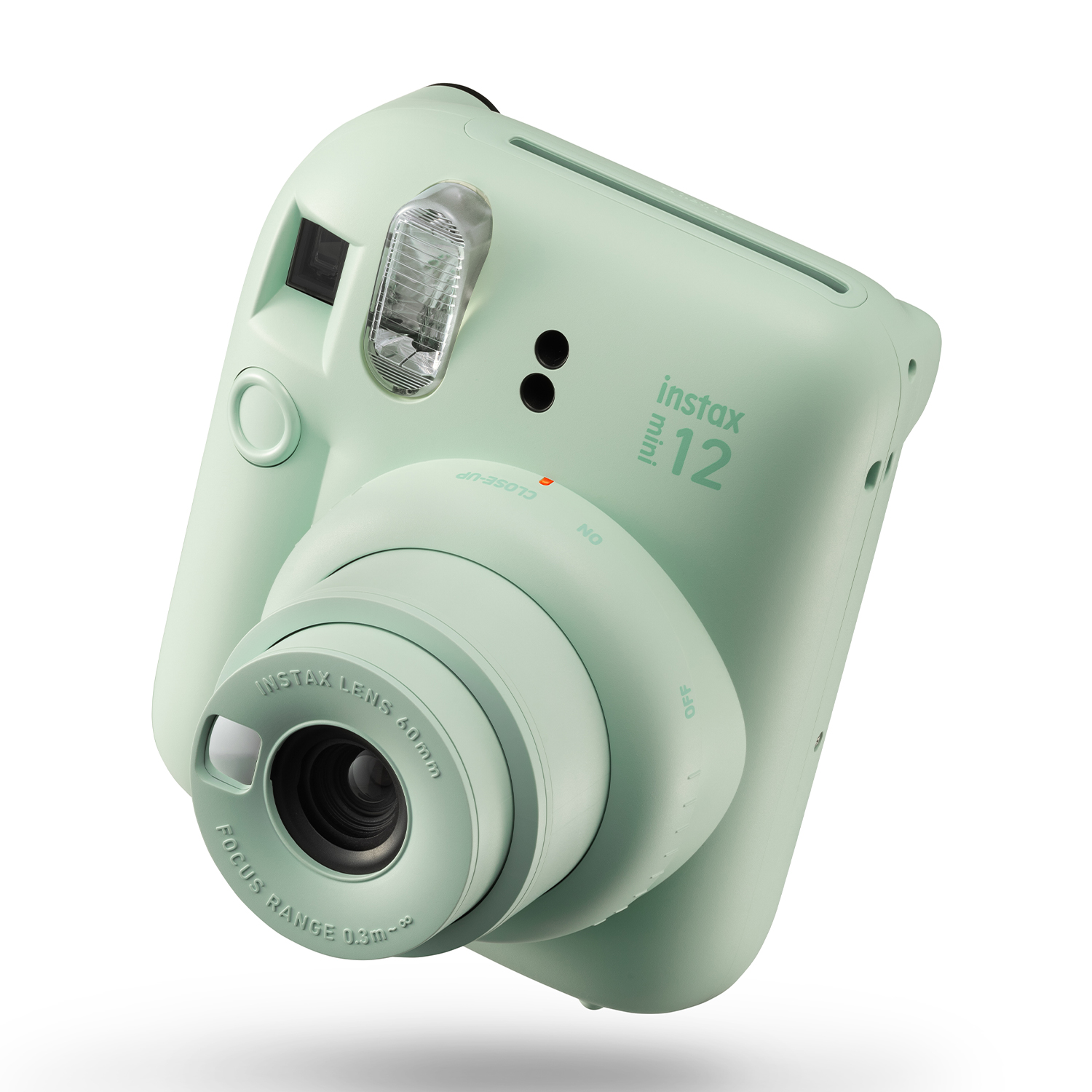 Una fotocamera Instax Mini 12 verde menta su sfondo bianco. L'obiettivo è visibile.
