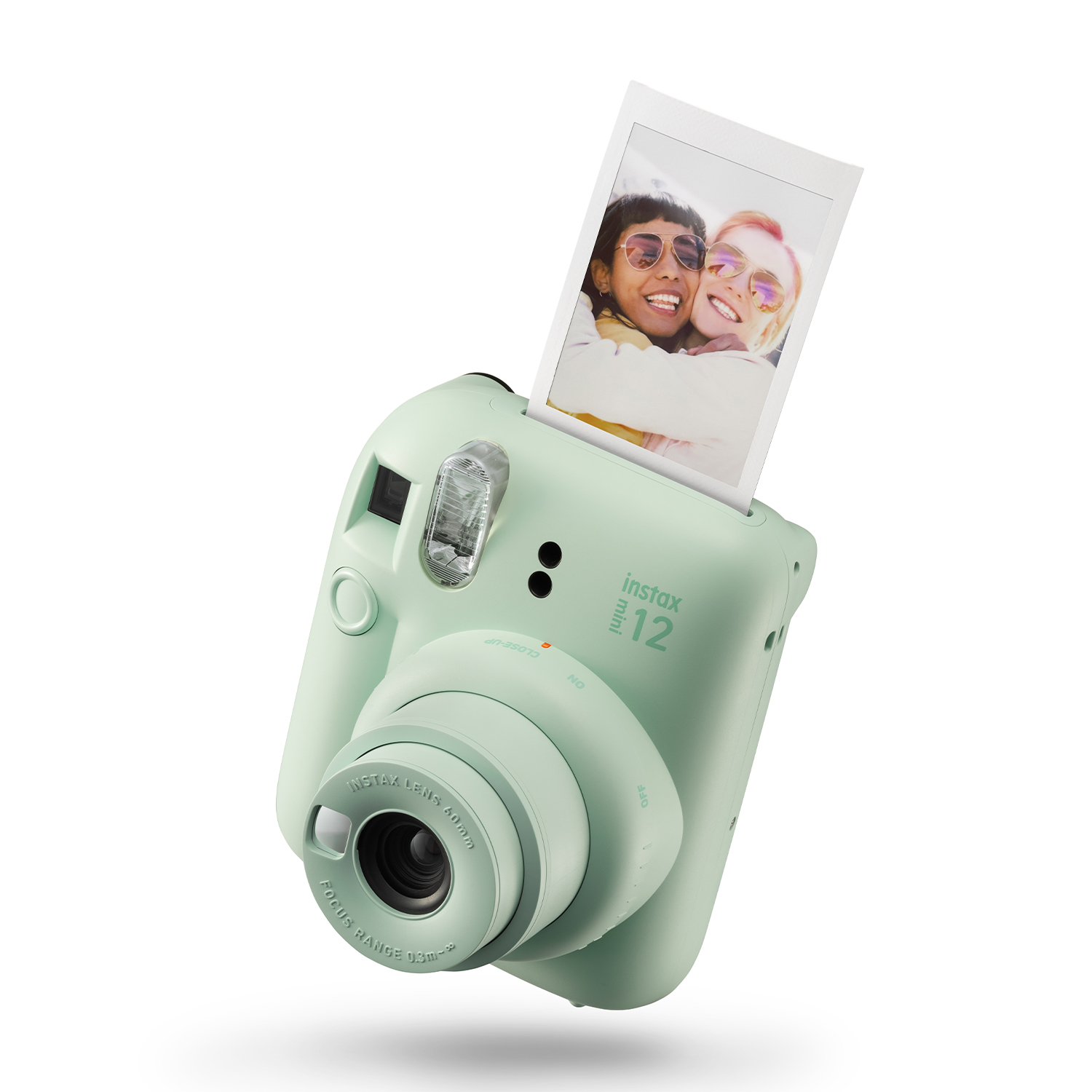 Fotocamera Instax Mini 12 verde menta con foto che viene espulsa.