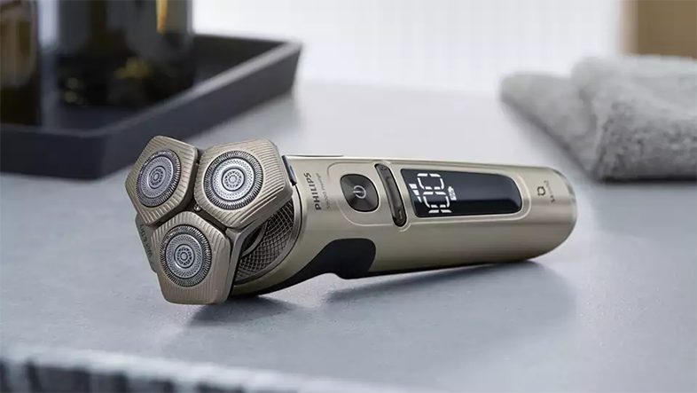 Egy Philips elektromos borotva szürke felületen. A borotván három fej és digitális kijelző található.