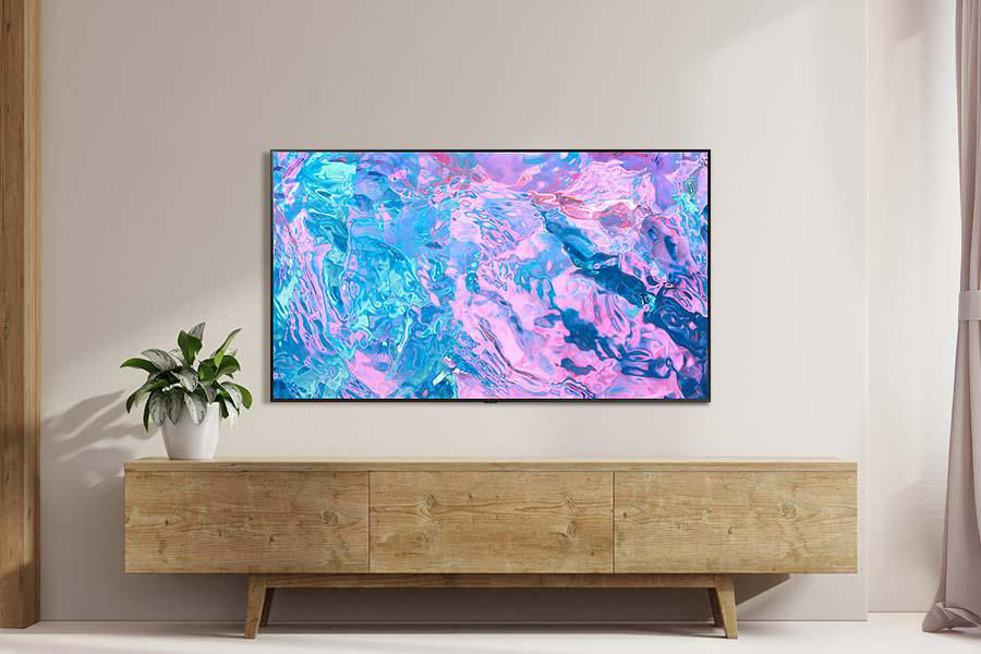 Ein Fernseher mit farbenfrohem, abstraktem Bild steht auf einem Holzschrank in einem Raum.