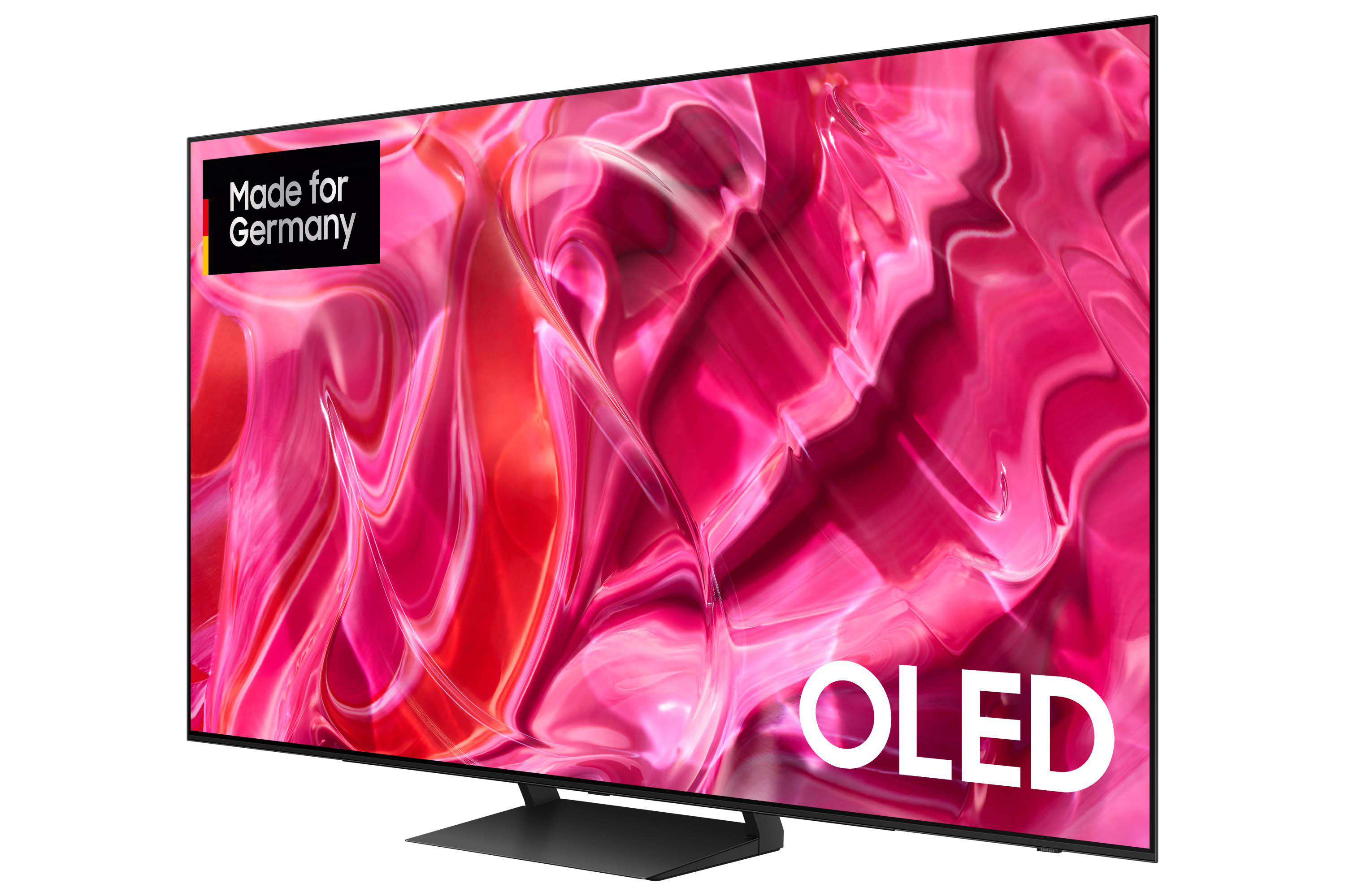 Ein moderner Fernsehbildschirm mit einem rosa-weißen Wirbeldesign auf einem schwarzen Ständer.
