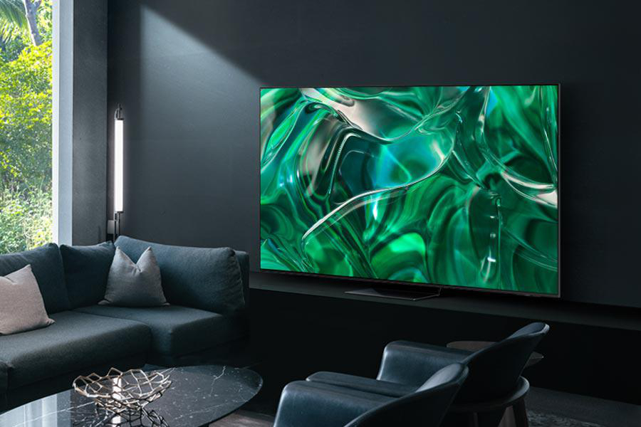 Wohnzimmer mit großem Fernseher, der ein grünes abstraktes Muster zeigt, Sofa und Sessel.
