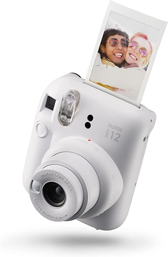 Una cámara instax mini 12 blanca está en ángulo, con una foto saliendo por la parte superior.